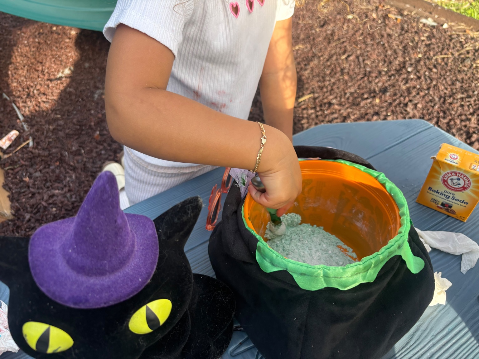Child stirring baking soda in Halloween cauldron