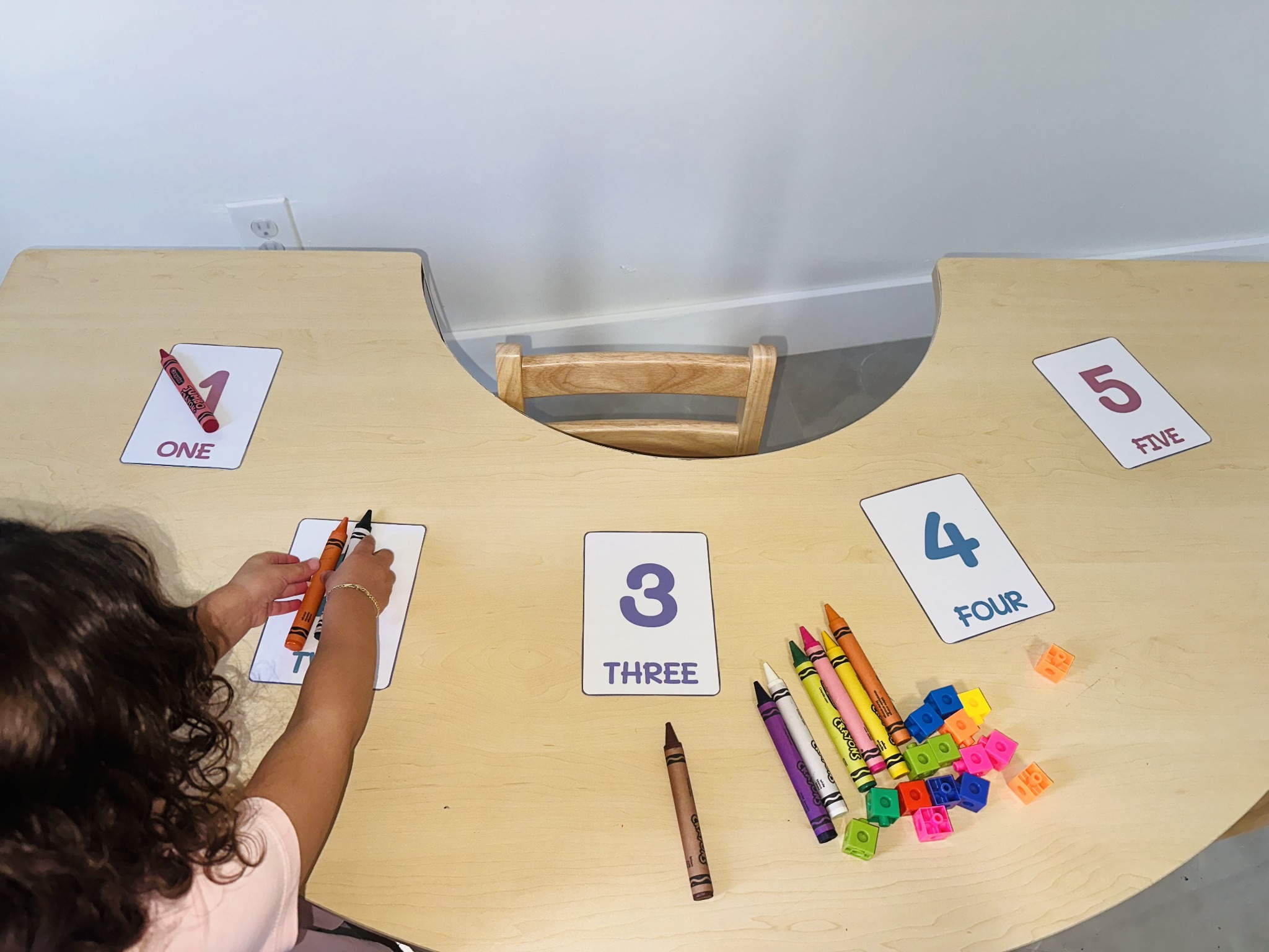Young child using crayons with number cards one through five