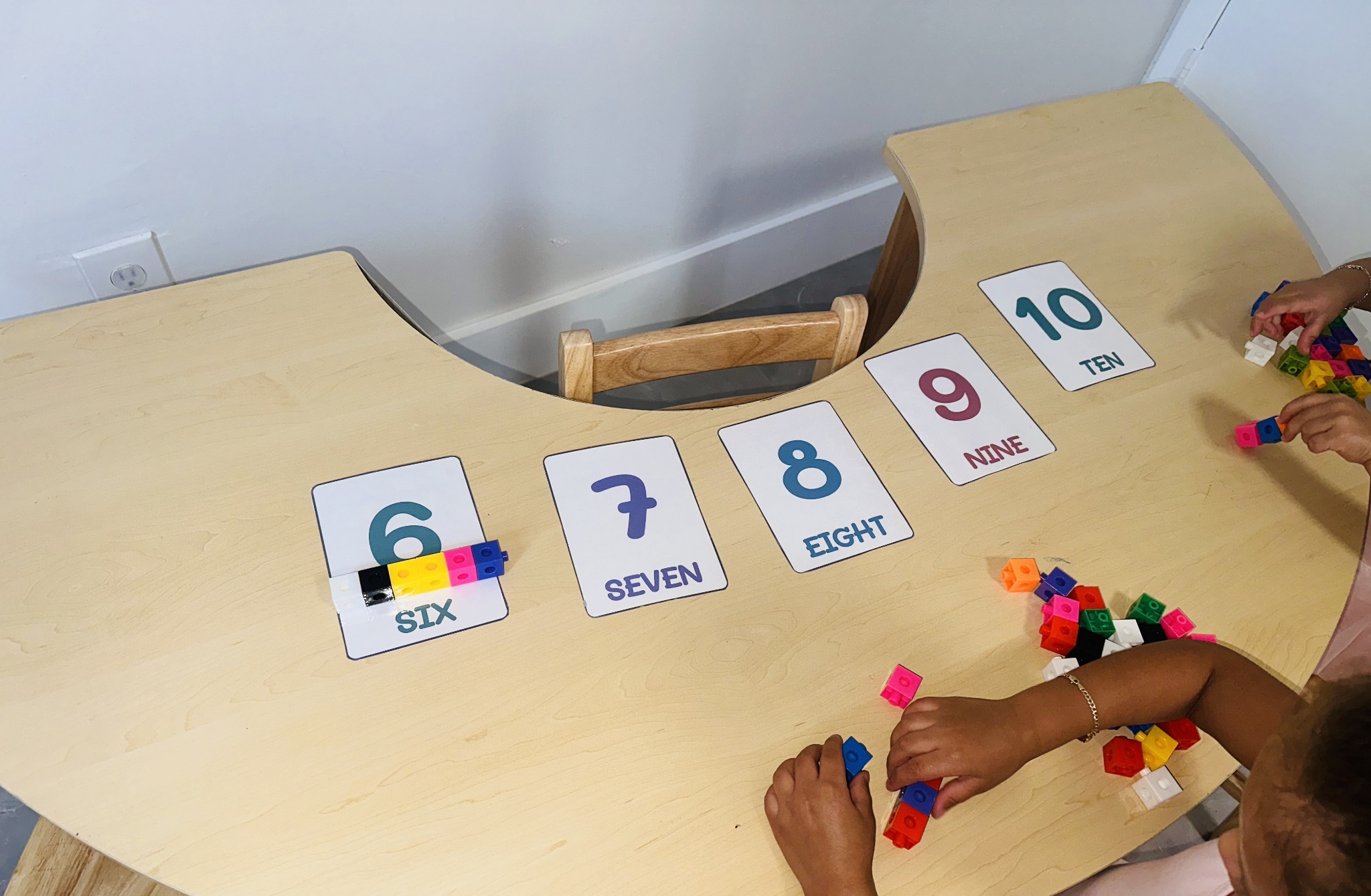 Child working on numbers six through ten with colorful linking cubes
