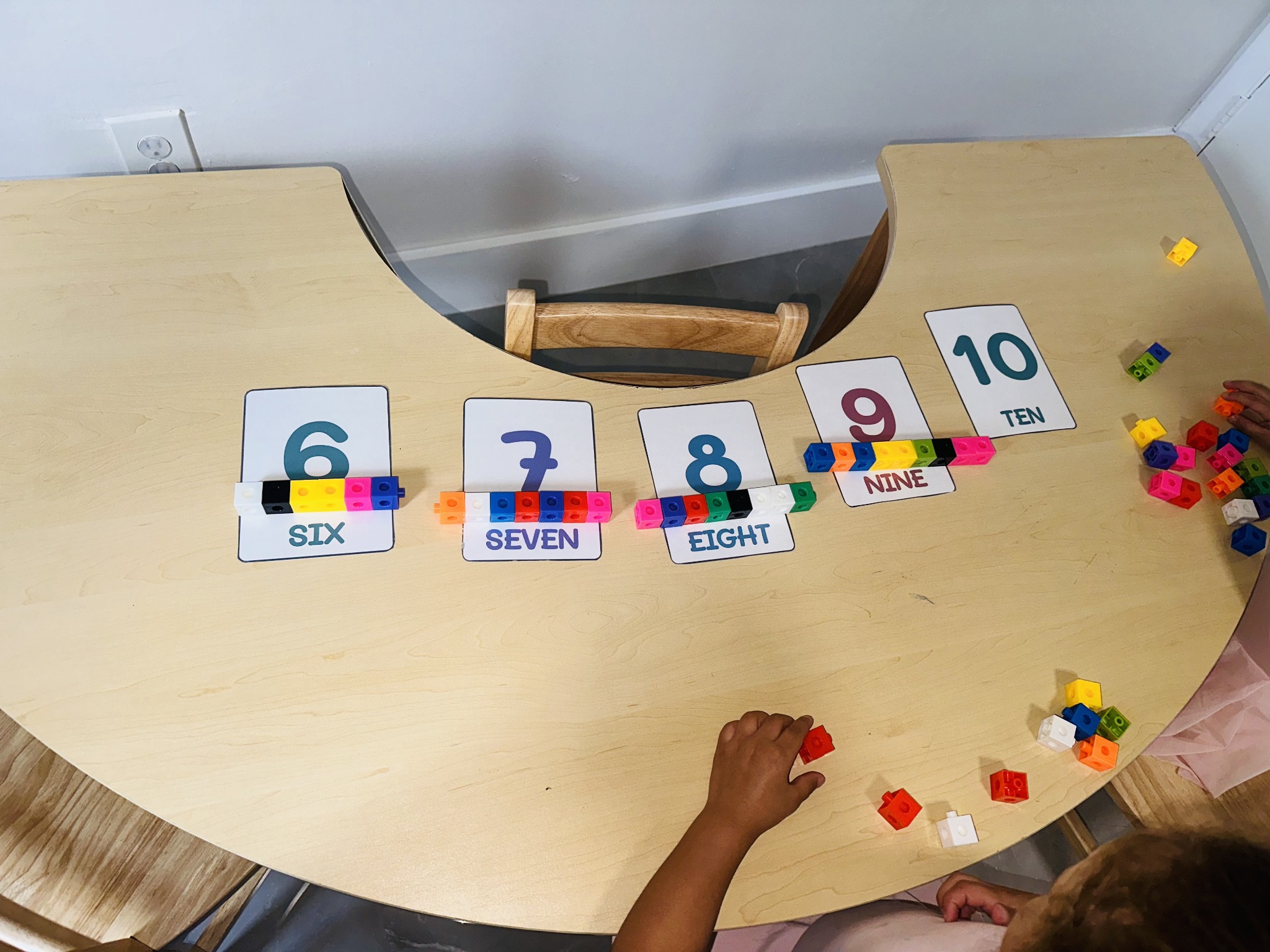 Number cards six through ten and colorful linking cube groups on a wooden homeschool table