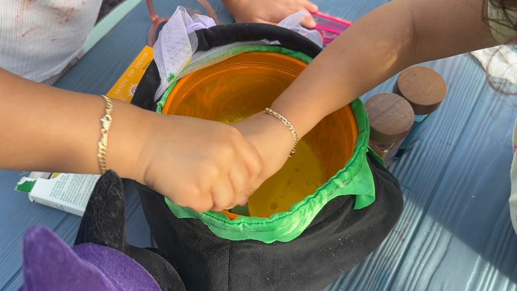Children mixing ingredients in Halloween cauldron